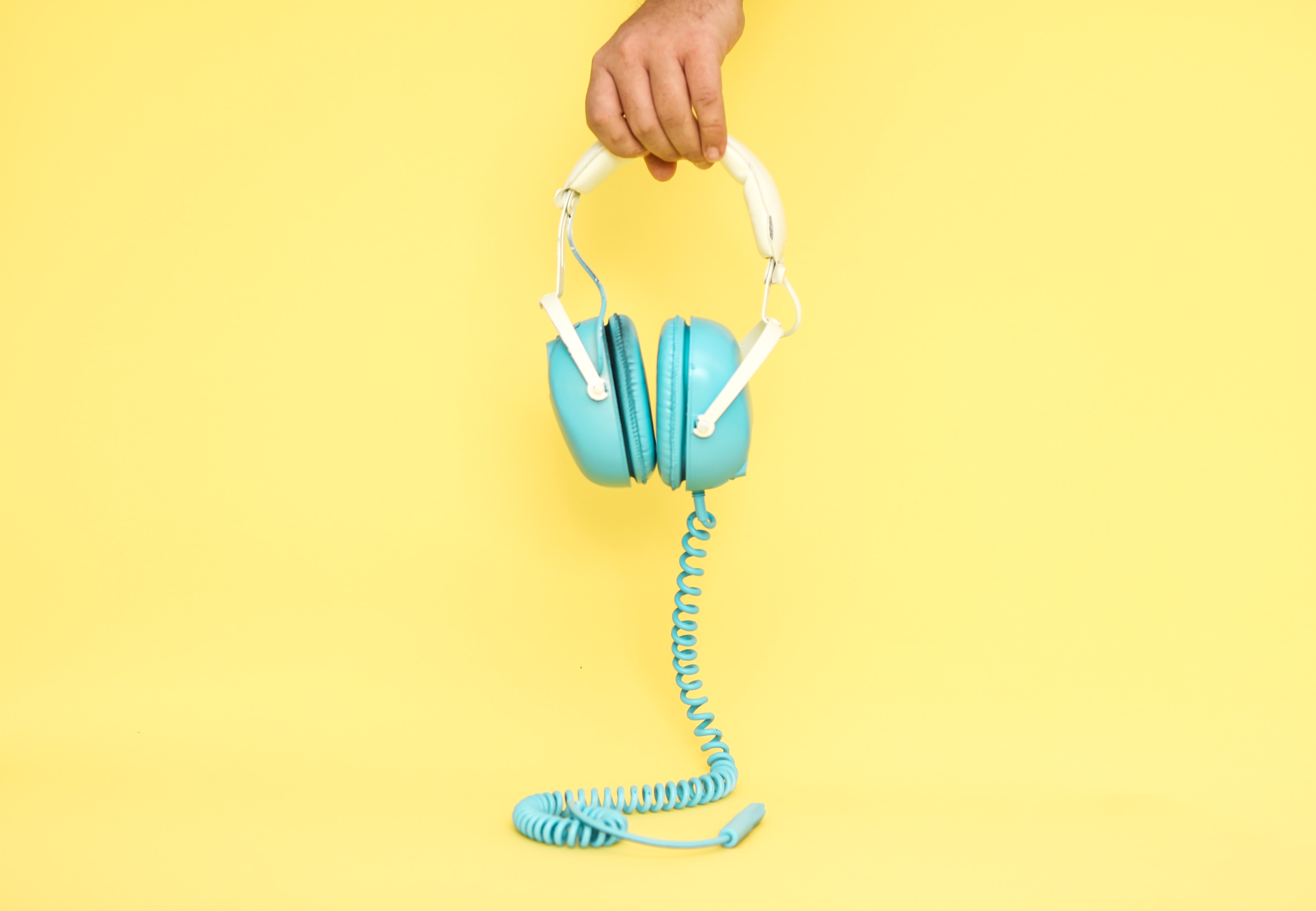 Picture of a pair of headphones held by the hand of a man.
Photo by Alex Gruber on Unsplash